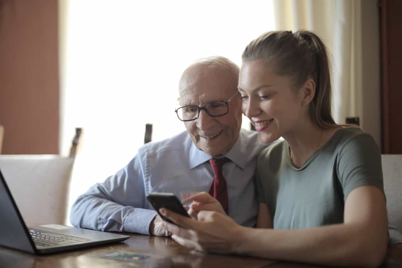 a younger woman showing an older man a phone