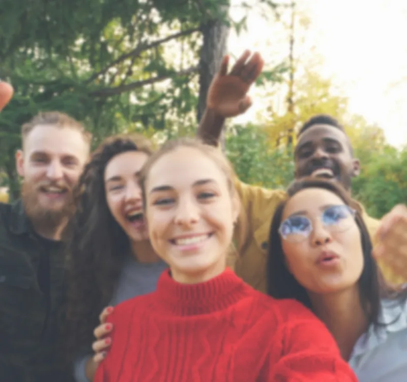 A group of friends smiling and waving at the camera